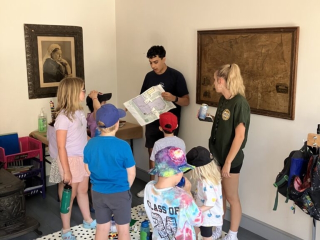 Children work with the camp councellor on a scavenger hunt